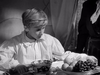 Movie still from “Oliver Twist” (1948), directed by David Lean – A young boy sitting at a table with a bowl of fruit; Medium shot, High angle