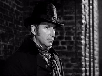 Movie still from “Oliver Twist” (1948), directed by David Lean – A man wearing a top hat and a long coat; Close Up shot, Low angle