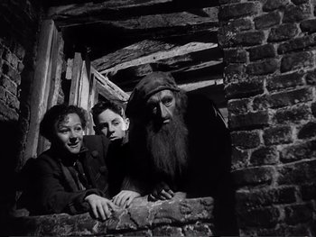 Movie still from “Oliver Twist” (1948), directed by David Lean – A group of people standing next to each other in a building; Medium shot, Low angle