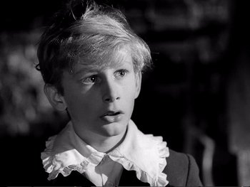 Movie still from “Oliver Twist” (1948), directed by David Lean – A young boy wearing a ruffle collar and a suit; Close Up shot, High angle