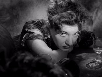 Movie still from “Oliver Twist” (1948), directed by David Lean – An old black and white photo of a woman leaning on a table; Close Up shot, High angle