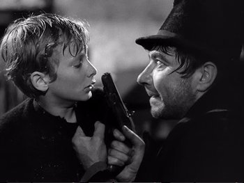 Movie still from “Oliver Twist” (1948), directed by David Lean – A young boy holding a gun next to an older man; Close Up shot, Over the shoulder angle