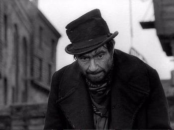 Movie still from “Oliver Twist” (1948), directed by David Lean – An old man wearing a hat and a coat; Medium shot, Low angle