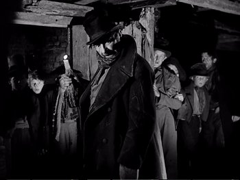 Movie still from “Oliver Twist” (1948), directed by David Lean – A group of men standing in a room with guns; Medium shot, Low angle