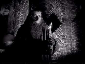 Movie still from “Oliver Twist” (1948), directed by David Lean – An old man with a long beard holding a lit candle; Medium shot, Low angle