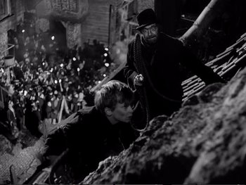 Movie still from “Oliver Twist” (1948), directed by David Lean – A man and a boy are climbing up a hill; Medium shot, High angle