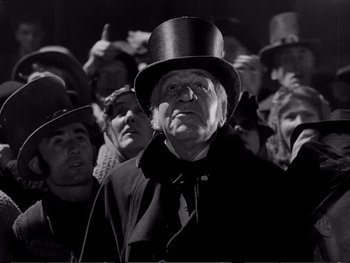 Movie still from “Oliver Twist” (1948), directed by David Lean – An old man wearing a top hat in front of a group of people; Close Up shot, Low angle
