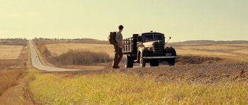 Movie still from “On the Road” (2012), directed by Walter Salles – A man walking next to an old black truck; Wide shot, Low angle