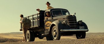 Movie still from “On the Road” (2012), directed by Walter Salles – Two men riding in the back of an old truck; Wide shot, Low angle