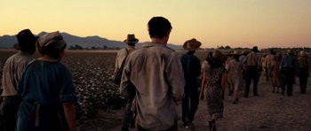 Movie still from “On the Road” (2012), directed by Walter Salles – A group of people walking across a dirt field; Medium shot, Over the shoulder angle