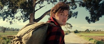 Movie still from “On the Road” (2012), directed by Walter Salles – A man with a backpack walking on a dirt road; Close Up shot, Low angle