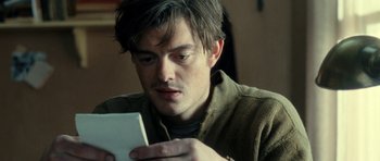 Movie still from “On the Road” (2012), directed by Walter Salles – A man looking at his cell phone while sitting at a table; Close Up shot, Over the shoulder angle