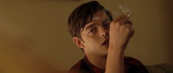 Movie still from “On the Road” (2012), directed by Walter Salles – A young man smoking a cigarette in a room; Close Up shot, Over the shoulder angle