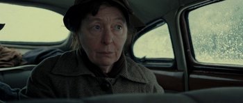 Movie still from “On the Road” (2012), directed by Walter Salles – An older woman sitting in the back seat of a car; Close Up shot, Over the shoulder angle