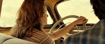Movie still from “On the Road” (2012), directed by Walter Salles – A young girl is driving a car in the road; Medium shot, Low angle