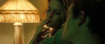 Movie still from “On the Road” (2012), directed by Walter Salles – A woman smoking a cigarette in a room lit by a lamp; Close Up shot, Over the shoulder angle