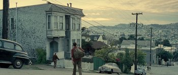Movie still from “On the Road” (2012), directed by Walter Salles – A man standing on the side of a road near a house; Wide shot, Low angle