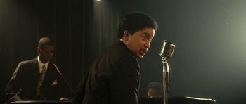 Movie still from “On the Road” (2012), directed by Walter Salles – A man standing next to a microphone on a stage; Close Up shot, Low angle