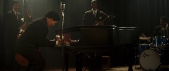 Movie still from “On the Road” (2012), directed by Walter Salles – Two men in suits are playing piano and guitar in front of a microphone; Medium shot, High angle