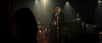 Movie still from “On the Road” (2012), directed by Walter Salles – A man standing in front of a microphone in front of a piano; Medium shot, Over the shoulder angle