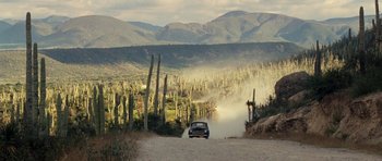 Movie still from “On the Road” (2012), directed by Walter Salles – A car driving down a dirt road near tall cacti; Extreme Wide shot, Low angle