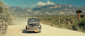 Movie still from “On the Road” (2012), directed by Walter Salles – An old car parked on the side of the road; Extreme Wide shot, Low angle