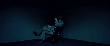 Movie still from “On the Road” (2012), directed by Walter Salles – A man sitting in a rocking chair in a dark room; Wide shot, High angle