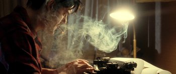 Movie still from “On the Road” (2012), directed by Walter Salles – A man smoking a cigarette while using an old fashioned typewriter; Close Up shot, Low angle