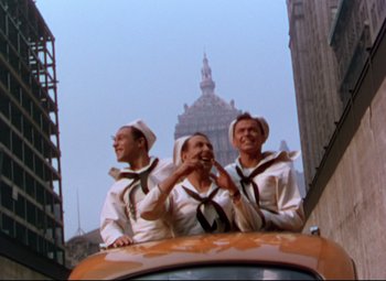 Movie still from “On the Town” (1949), directed by Gene Kelly – A group of men in sailor's uniforms standing on top of a car; Wide shot, Low angle