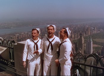 Movie still from “On the Town” (1949), directed by Gene Kelly – A group of men standing next to each other on top of a building; Wide shot, High angle