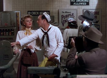 Movie still from “On the Town” (1949), directed by Gene Kelly – A man and a woman are standing in front of a camera; Medium shot, Over the shoulder angle