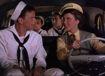Movie still from “On the Town” (1949), directed by Gene Kelly – A couple of people that are sitting in the back of a car; Medium shot, Over the shoulder angle