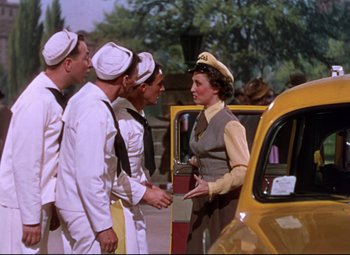 Movie still from “On the Town” (1949), directed by Gene Kelly – A group of men standing next to each other near a yellow taxi cab; Medium shot, High angle
