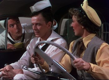 Movie still from “On the Town” (1949), directed by Gene Kelly – A man and two women sitting in the back of a car; Medium shot, High angle