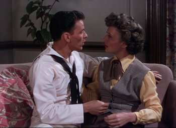 Movie still from “On the Town” (1949), directed by Gene Kelly – A man and a woman sitting on a couch together; Medium shot, High angle