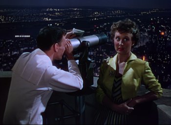 Movie still from “On the Town” (1949), directed by Gene Kelly – A man and a woman looking through a telescope at night; Medium shot, High angle