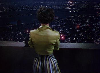 Movie still from “On the Town” (1949), directed by Gene Kelly – A woman standing on top of a building looking out over a city at night; Medium shot, High angle