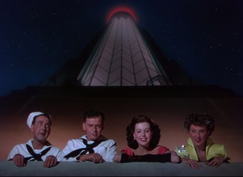Movie still from “On the Town” (1949), directed by Gene Kelly – A group of people standing next to each other in front of a building at night; Wide shot, Low angle