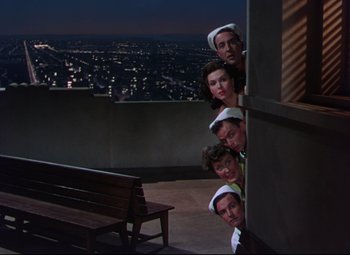 Movie still from “On the Town” (1949), directed by Gene Kelly – A group of people standing next to each other on top of a building; Wide shot, High angle
