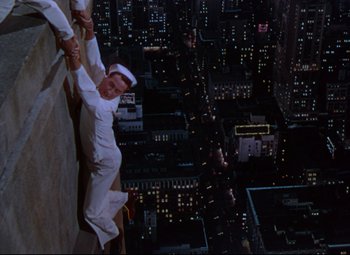 Movie still from “On the Town” (1949), directed by Gene Kelly – A man climbing a wall in the middle of a city at night; Wide shot, Overhead angle