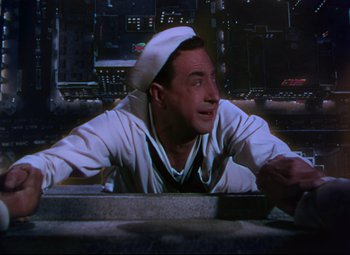 Movie still from “On the Town” (1949), directed by Gene Kelly – A man wearing a sailor's hat sitting at a table; Medium shot, Low angle