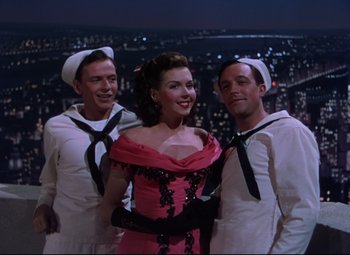 Movie still from “On the Town” (1949), directed by Gene Kelly – A woman in a red dress and two men in sailor's hats; Medium shot, High angle