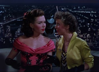 Movie still from “On the Town” (1949), directed by Gene Kelly – Two women are standing next to each other in front of a cityscape; Medium shot, High angle