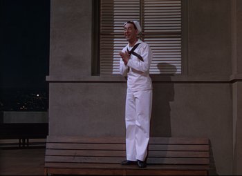 Movie still from “On the Town” (1949), directed by Gene Kelly – A man dressed as a sailor standing on a bench; Wide shot, Low angle