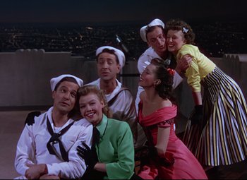 Movie still from “On the Town” (1949), directed by Gene Kelly – A group of people in sailor outfits posing for a picture; Medium shot, High angle