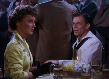 Movie still from “On the Town” (1949), directed by Gene Kelly – A man and a woman sitting at a dinner table; Medium shot, Over the shoulder angle