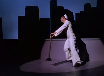 Movie still from “On the Town” (1949), directed by Gene Kelly – A man in a sailor's uniform holding a broom; Wide shot, Low angle