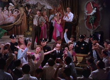 Movie still from “On the Town” (1949), directed by Gene Kelly – A group of people standing in front of a stage; Wide shot, High angle