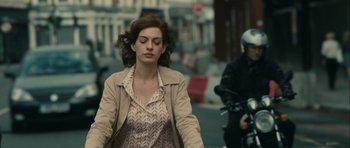 Movie still from “One Day” (2011), directed by Lone Scherfig – A woman walking down a street with a motorcycle in the background; Medium shot, Over the shoulder angle