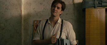 Movie still from “One Day” (2011), directed by Lone Scherfig – A young man holding an accordion in a room; Close Up shot, Low angle